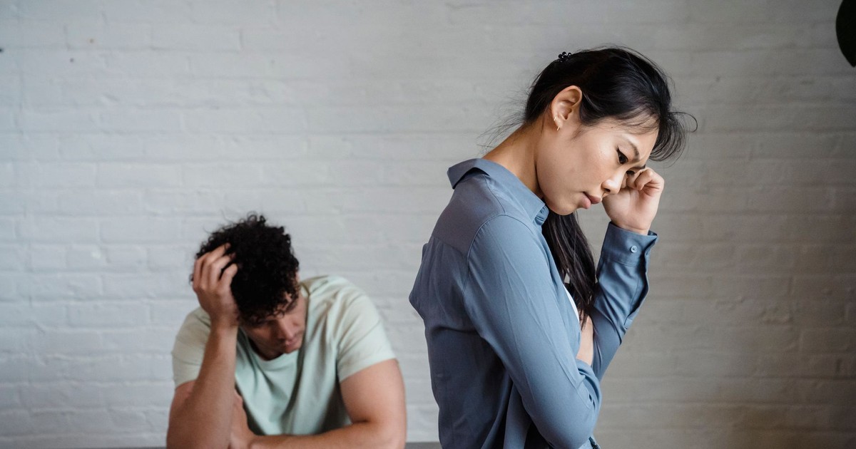 An Asian woman and man feeling misunderstood and frustrated in a relationship indoors.