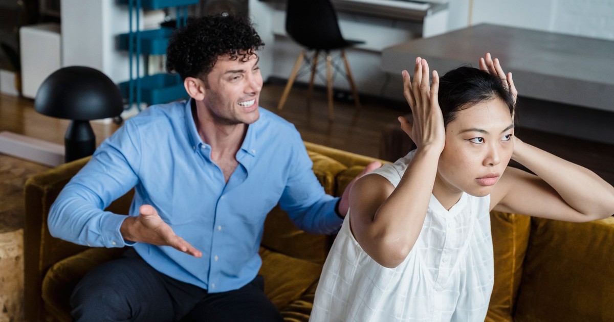 A man and woman in a heated argument sitting on a couch indoors.