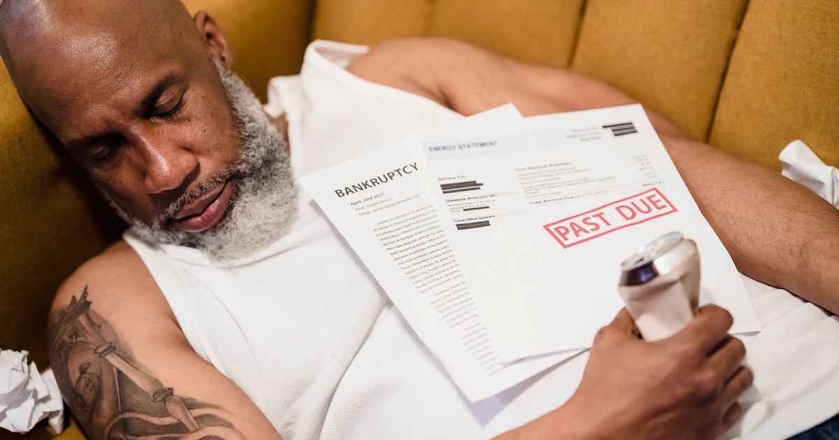 Sleeping man with financial documents, symbolizing stress and bankruptcy.