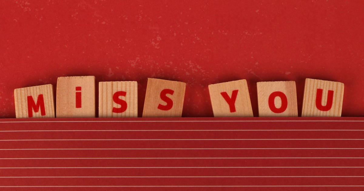 Wooden blocks with 'MISS YOU' text on a red background, expressing longing.