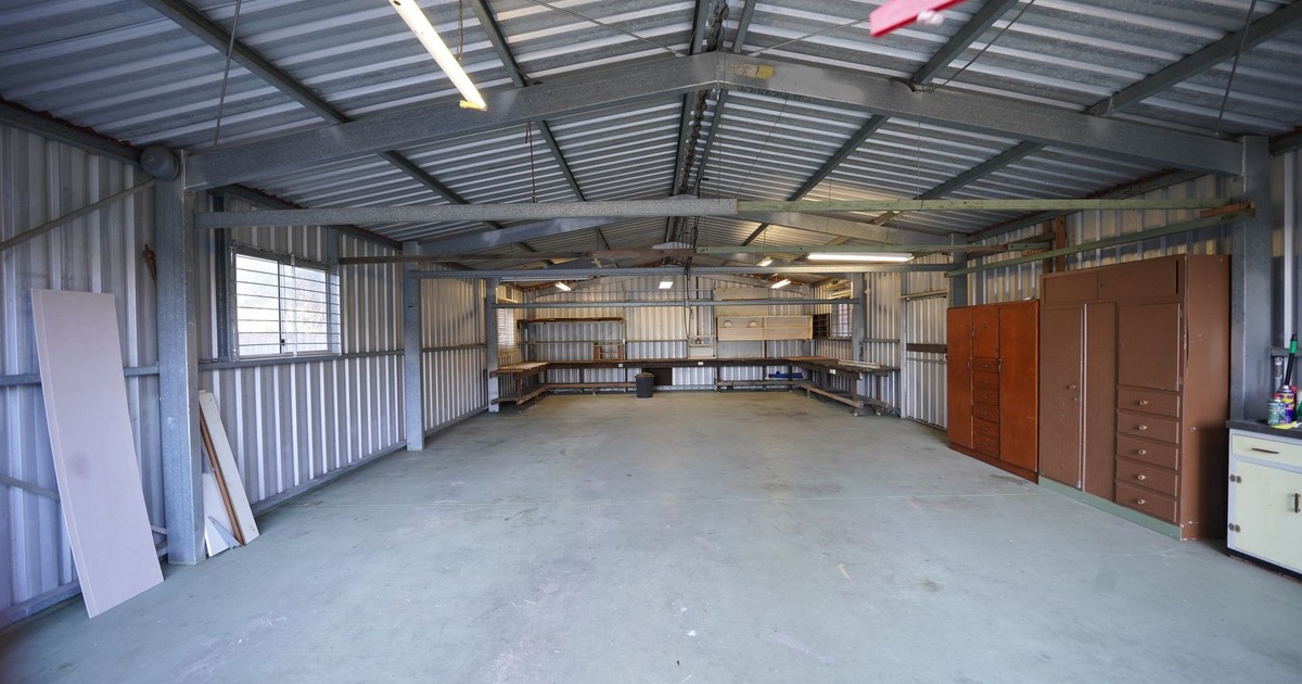 Empty industrial garage with metal walls and concrete floor ready for renovation or use.