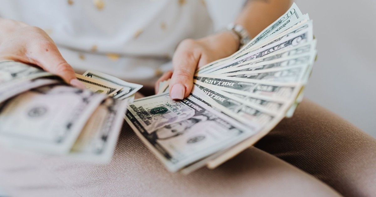 Close-up of hands holding and counting US dollar bills indoors.