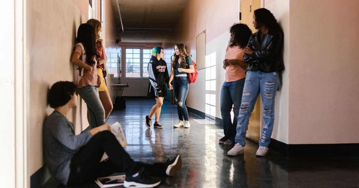 Students interact and relax between classes in a school's bright hallway.