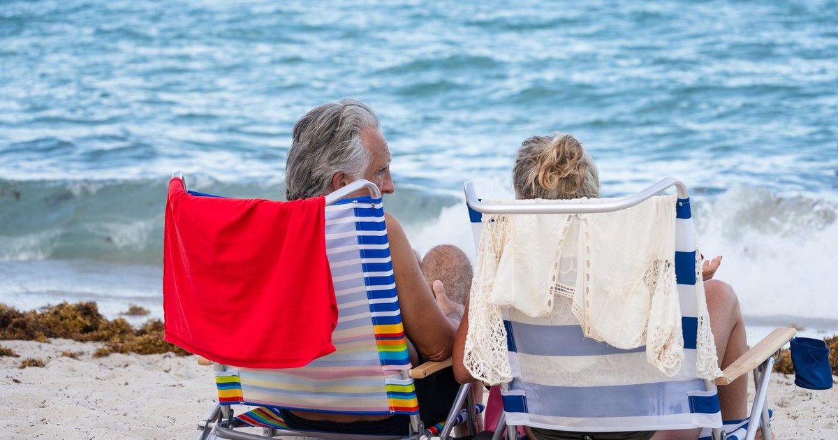 Senior couple relaxing on Miami Beach, enjoying the ocean view and summer sunshine.