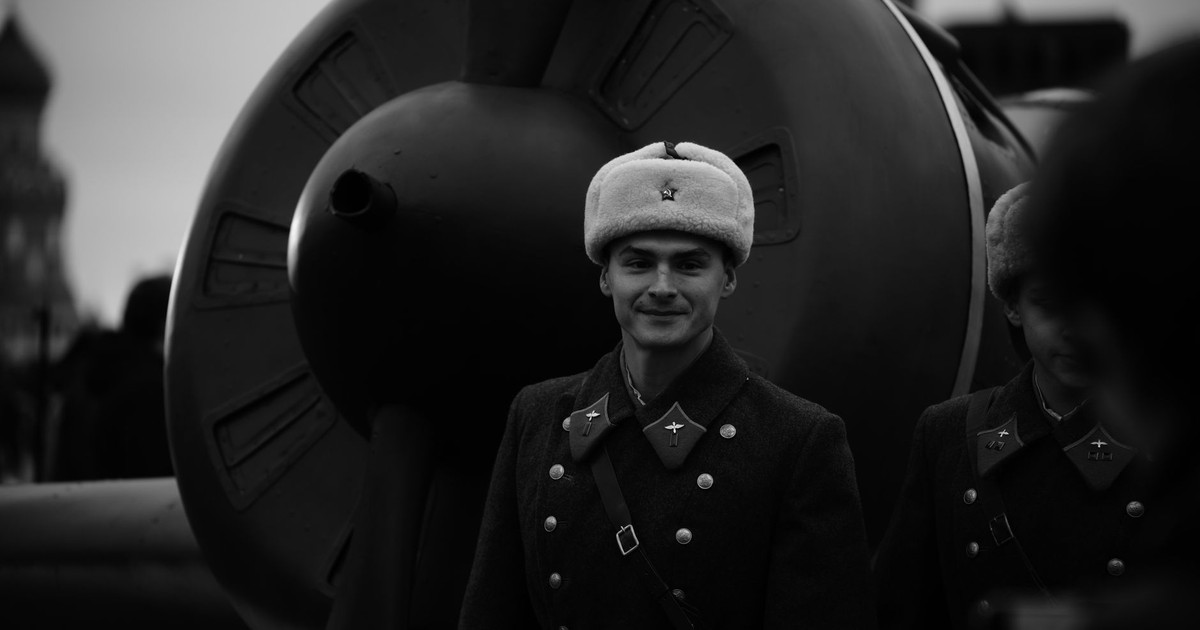 Black and white photo of Soviet soldiers in vintage uniforms beside an old aircraft.
