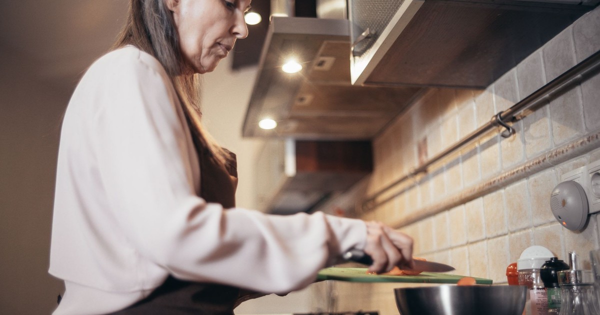 Senior woman preparing a meal in a modern home kitchen, focusing on healthy cooking.