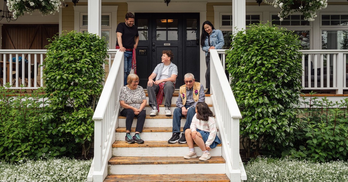 Multigenerational family enjoying a moment on porch steps surrounded by greenery.