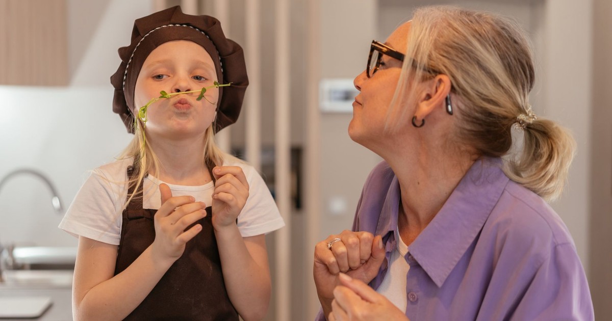 A grandmother and granddaughter share a playful moment in the kitchen, showcasing love and joy.