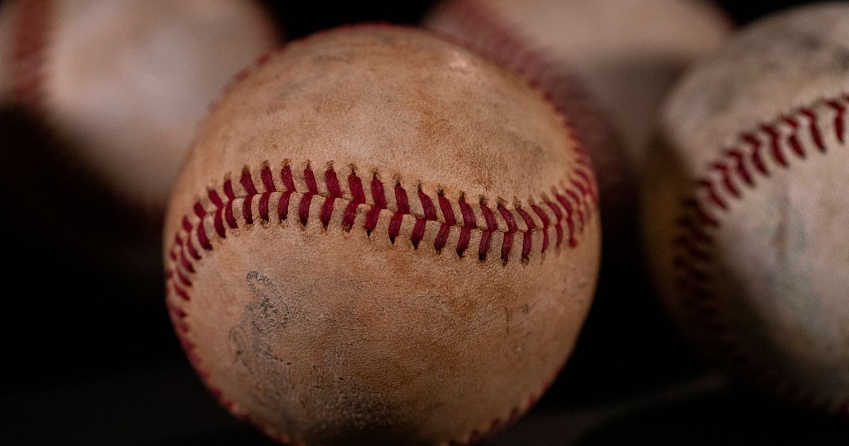 Weathered baseballs with red stitches against a blurred background, emphasizing texture and wear.
