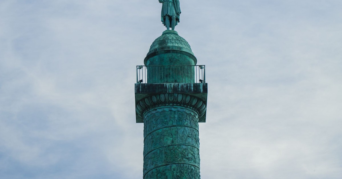 A detailed view of the Colonne Vendôme statue in Paris against a serene sky.