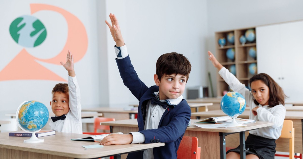 Students in a classroom eagerly raising their hands during a lesson.