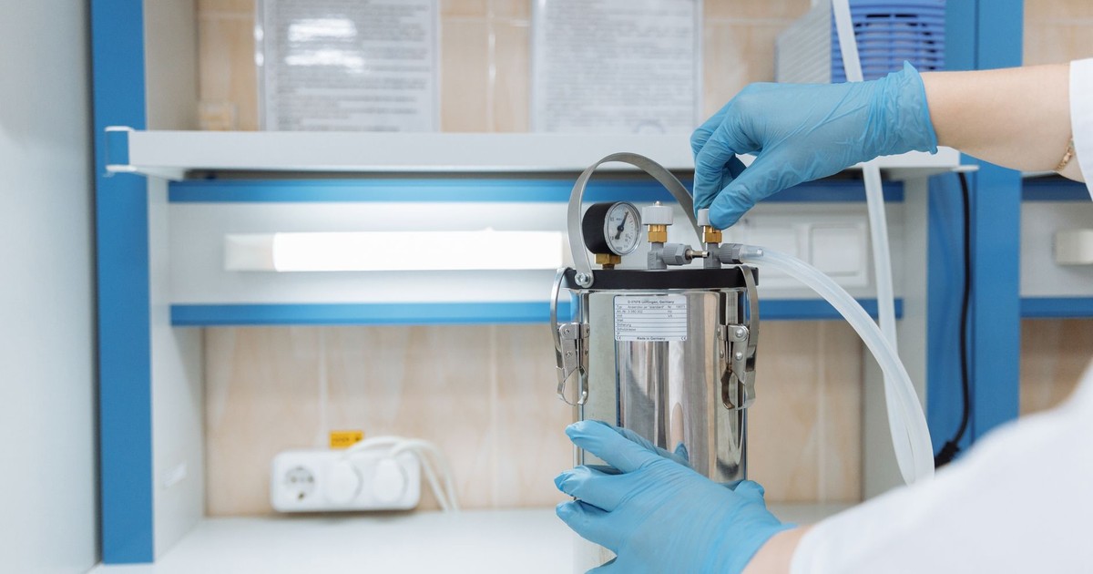 Scientist adjusting laboratory equipment with precision in a modern lab setting, wearing blue gloves.