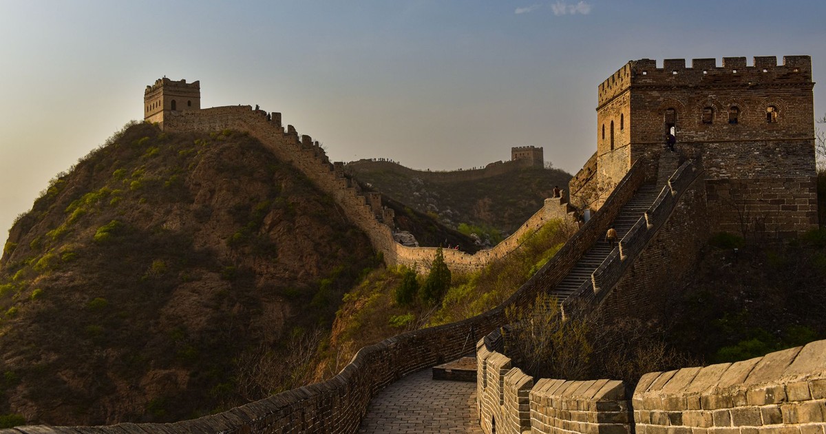 Majestic view of Great Wall of China winding over hilly terrain, captured at sunset.
