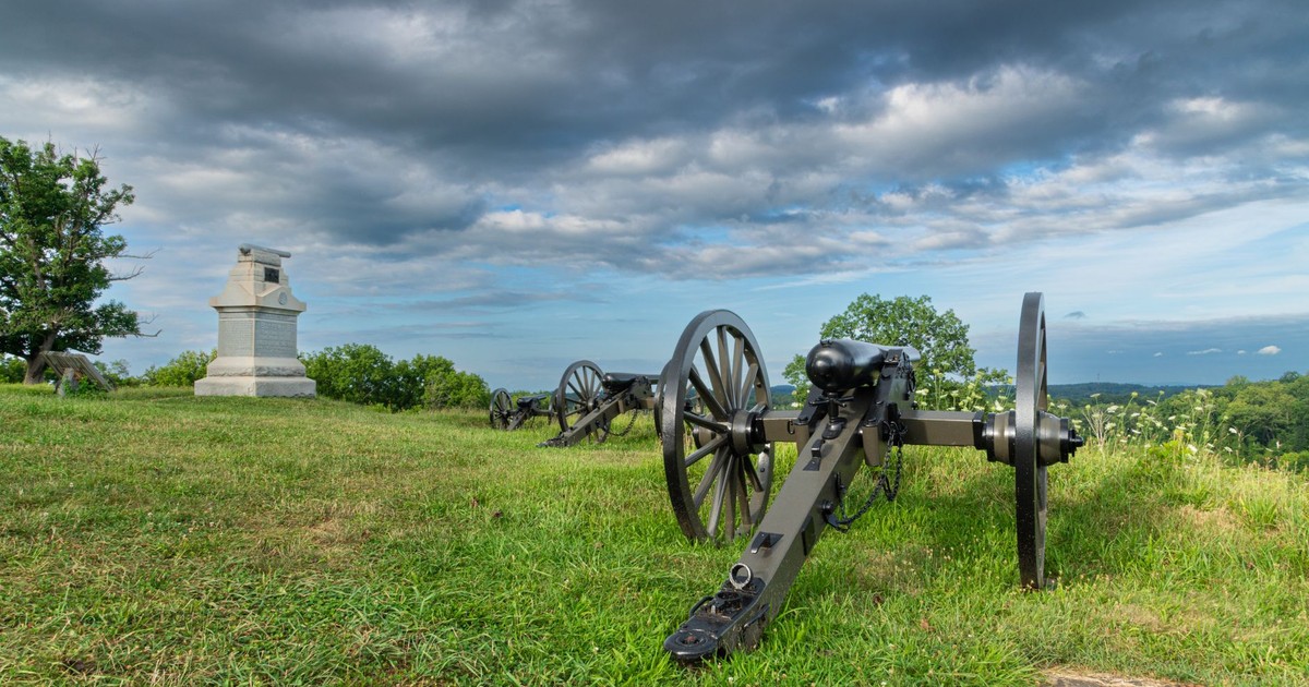 Historic cannons and memorial at Gettysburg, Pennsylvania, set against a dramatic sky.