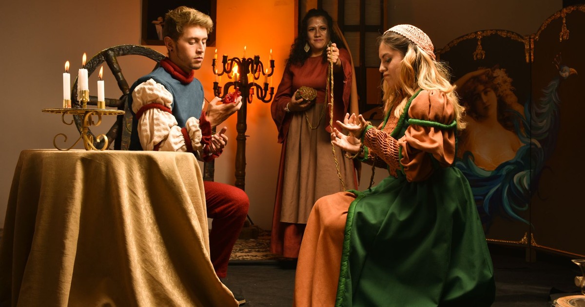 A captivating indoor scene of actors in Renaissance costumes performing on stage, lit by candlelight.