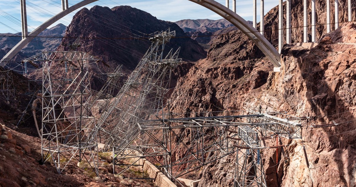 High-angle view of Hoover Dam bridge and power lines against rugged canyon backdrop, USA.