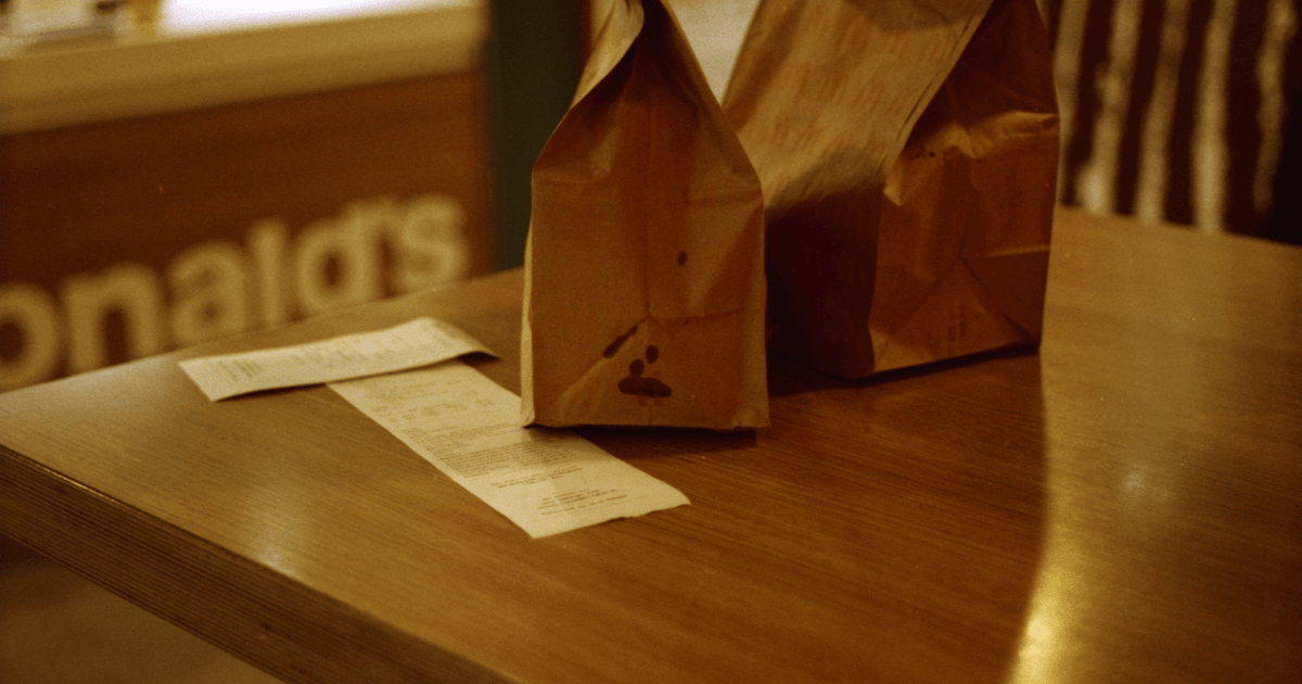Retro-style brown paper bags and receipt at McDonald's table evoke a nostalgic fast food experience.
