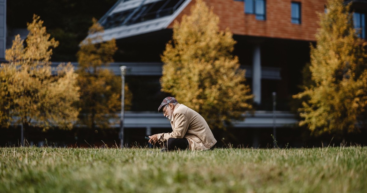 Elderly man in Berlin using smartphone outdoors in autumn.