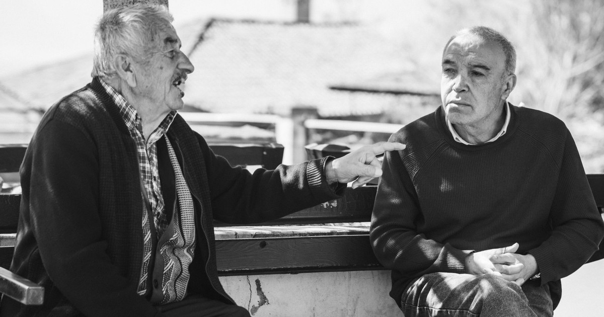 Two senior adults conversing outdoors, captured in black and white for a timeless feel.