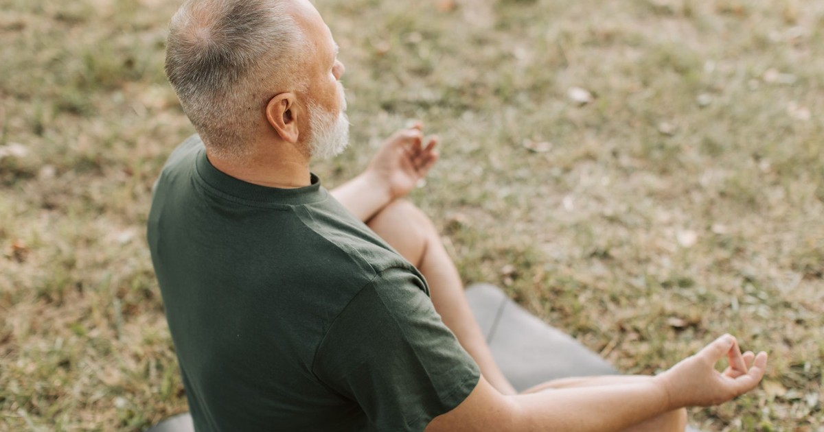 Senior man practicing yoga in a serene outdoor setting, promoting wellness and mindfulness.