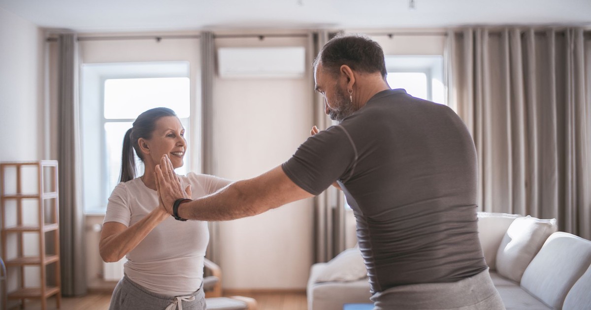 Senior couple engaging in fun exercises together at home, promoting fitness and bonding.