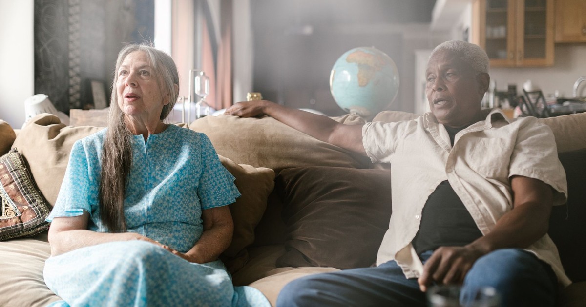 Senior couple sitting on sofa indoors, enjoying a peaceful moment together.