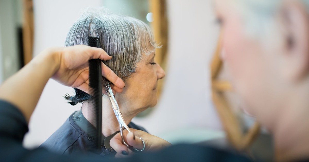 Elderly woman receiving a haircut in a trendy Portuguese hair salon.