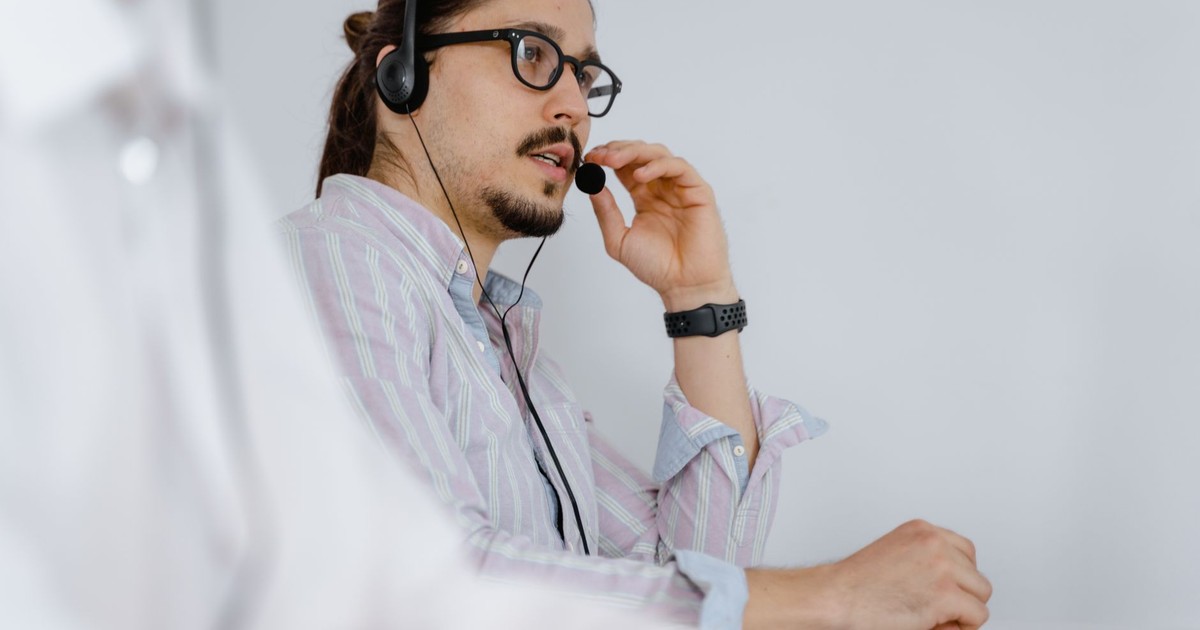Focused customer service agent speaking on a headset in a modern office environment.
