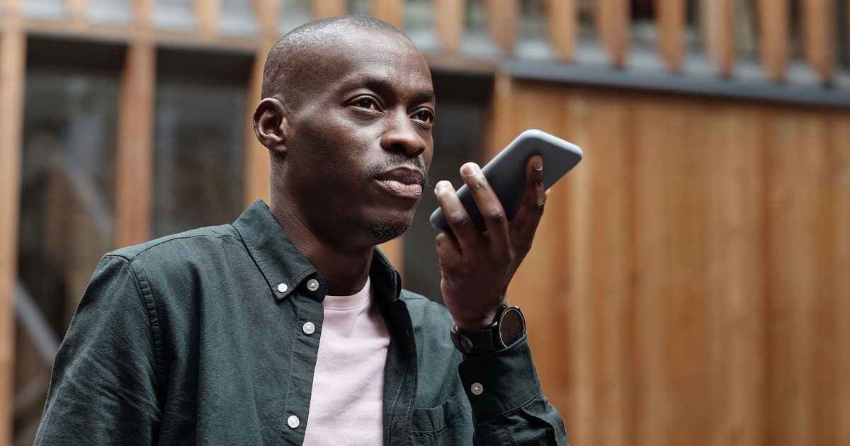 Stylish adult man using his smartphone for voice commands in an outdoor urban setting.