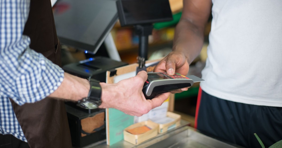 A customer making a payment with a credit card at a store checkout counter using a card reader.
