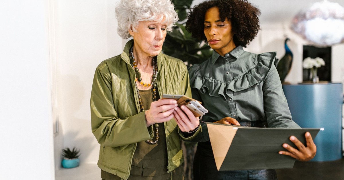 Two professional women discussing work-related documents in a stylish office setting.