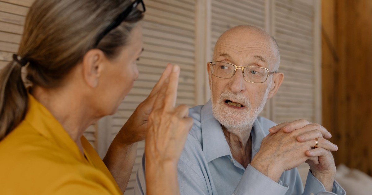 Elderly couple having an engaging conversation indoors, showcasing connection and emotion.