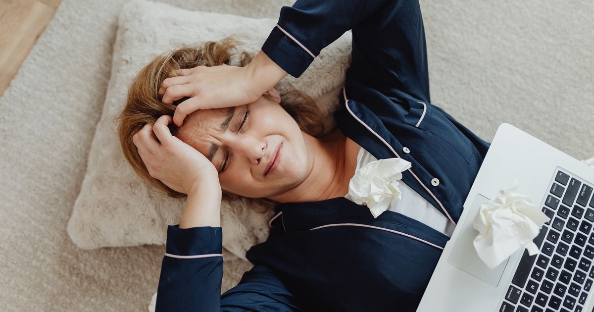 Overhead view of a frustrated woman in loungewear with a laptop and crumpled papers, facing remote work stress.