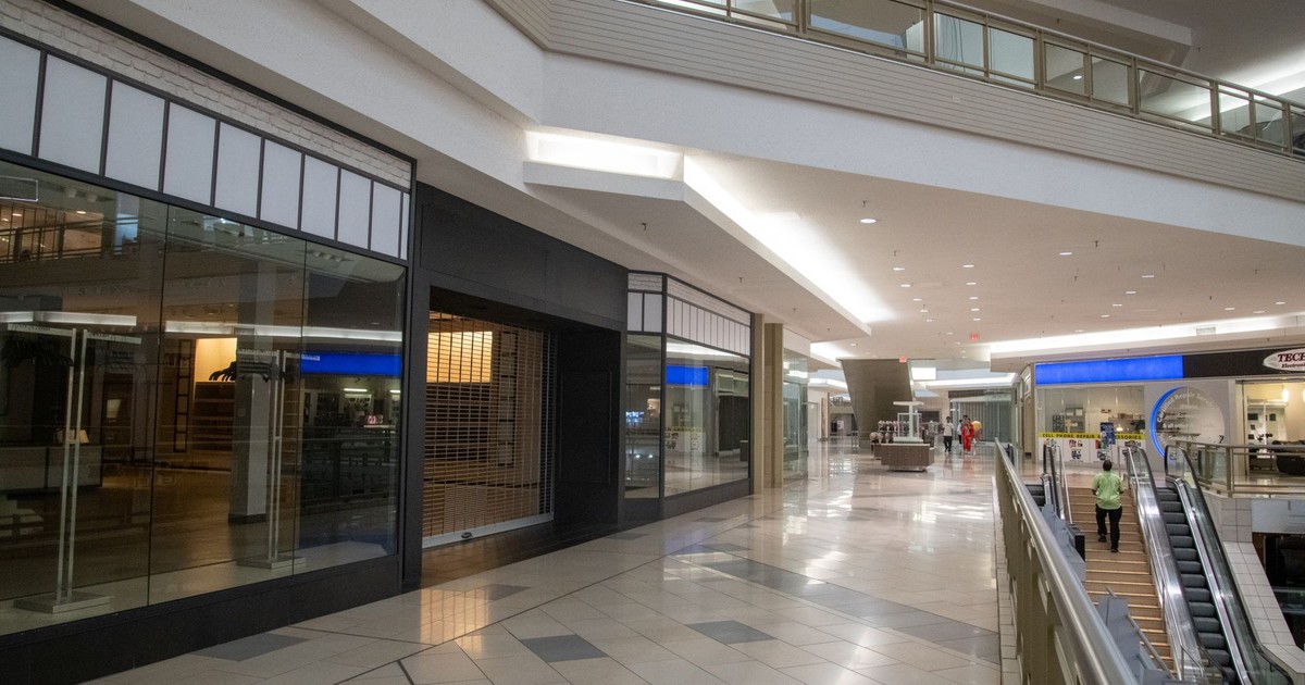 Spacious and contemporary mall interior with closed stores and escalator.