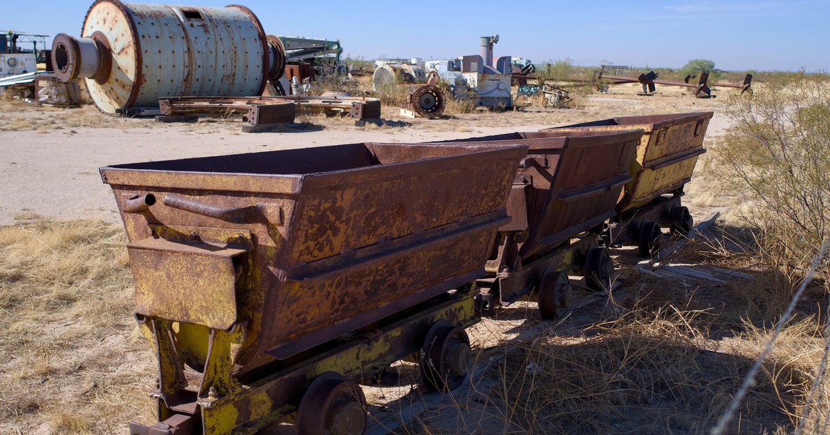 An abandoned industrial site with rusty mining carts and old machinery under a clear blue sky.