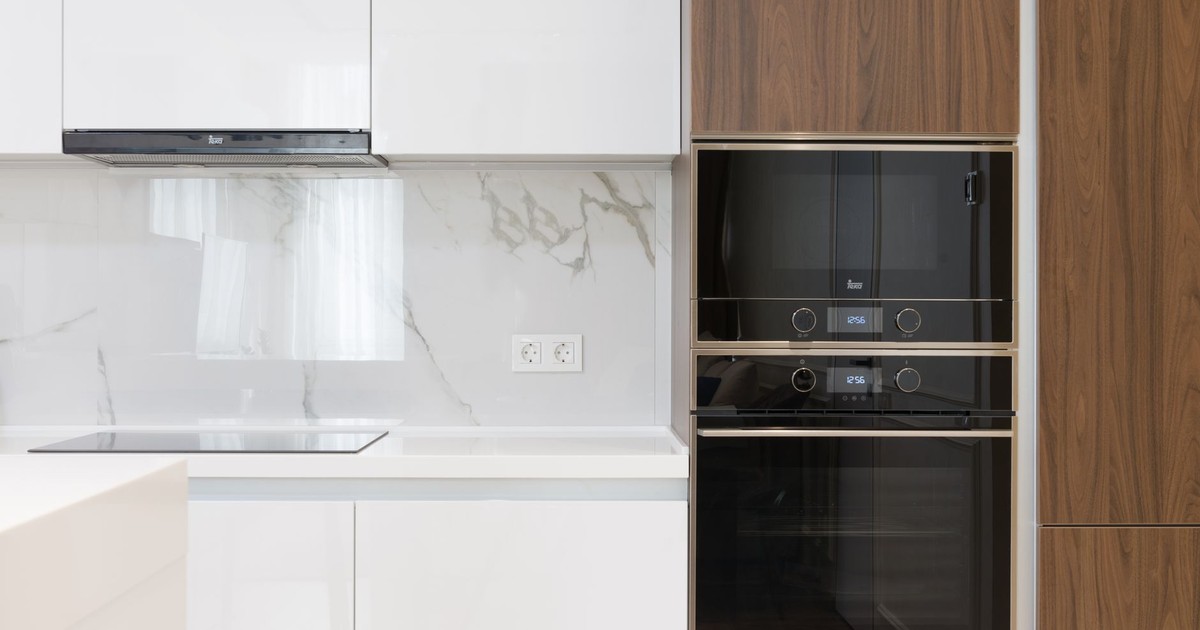 Modern interior of white and wooden kitchen with cabinets cupboards and built in appliances in contemporary flat