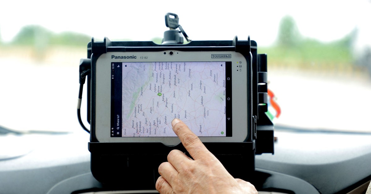 Close-up of hand interacting with GPS navigation on a car-mounted tablet screen, showcasing modern technology.