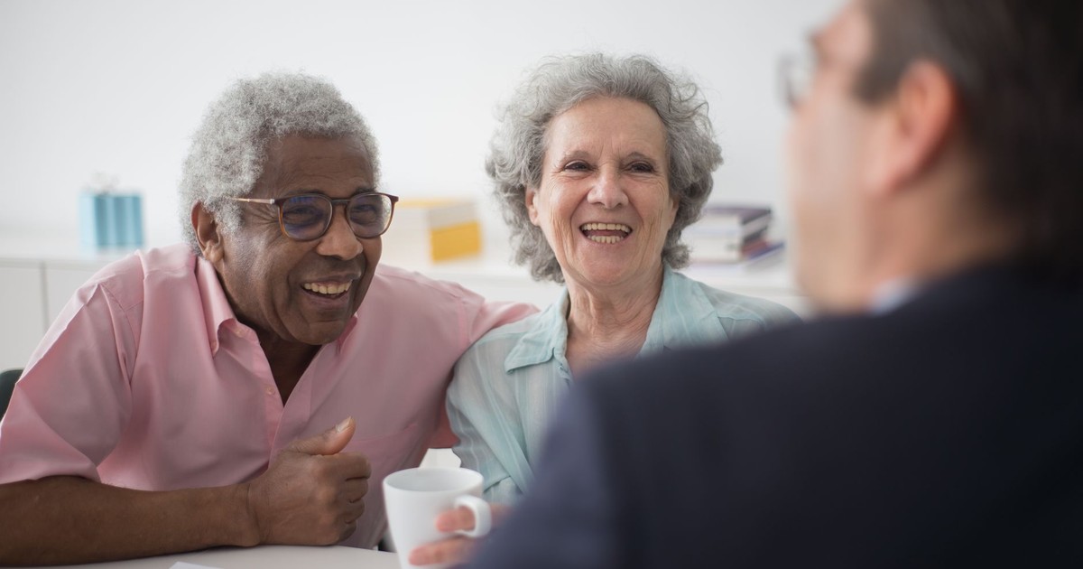 Happy elderly couple enjoying a conversation with a professional advisor indoors.