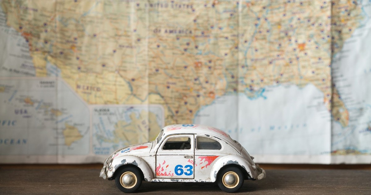 Close-up of a vintage toy car model with map background, symbolizing travel and exploration.