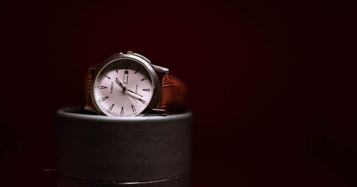 Stylish Timex watch with a brown leather strap elegantly displayed on a cylindrical stand.