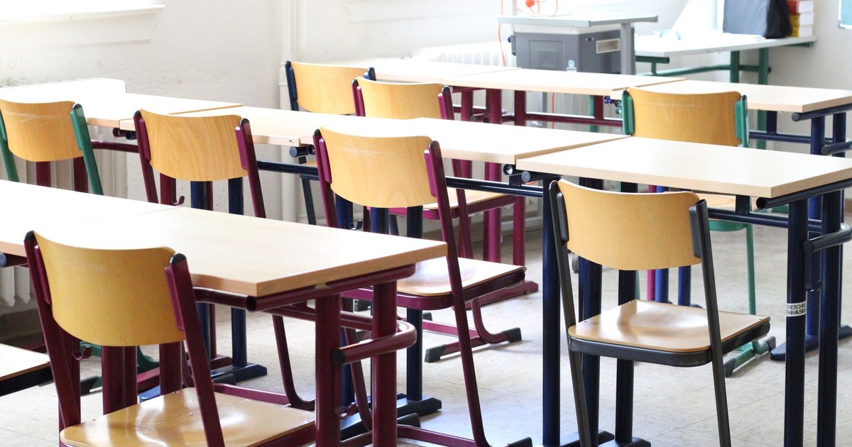 A bright empty classroom with wooden tables and chairs, ready for students.