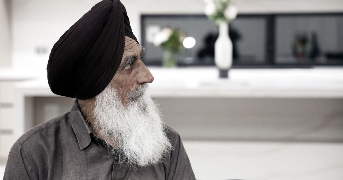 Portrait of an elderly man wearing a turban, indoors with a modern decor background.