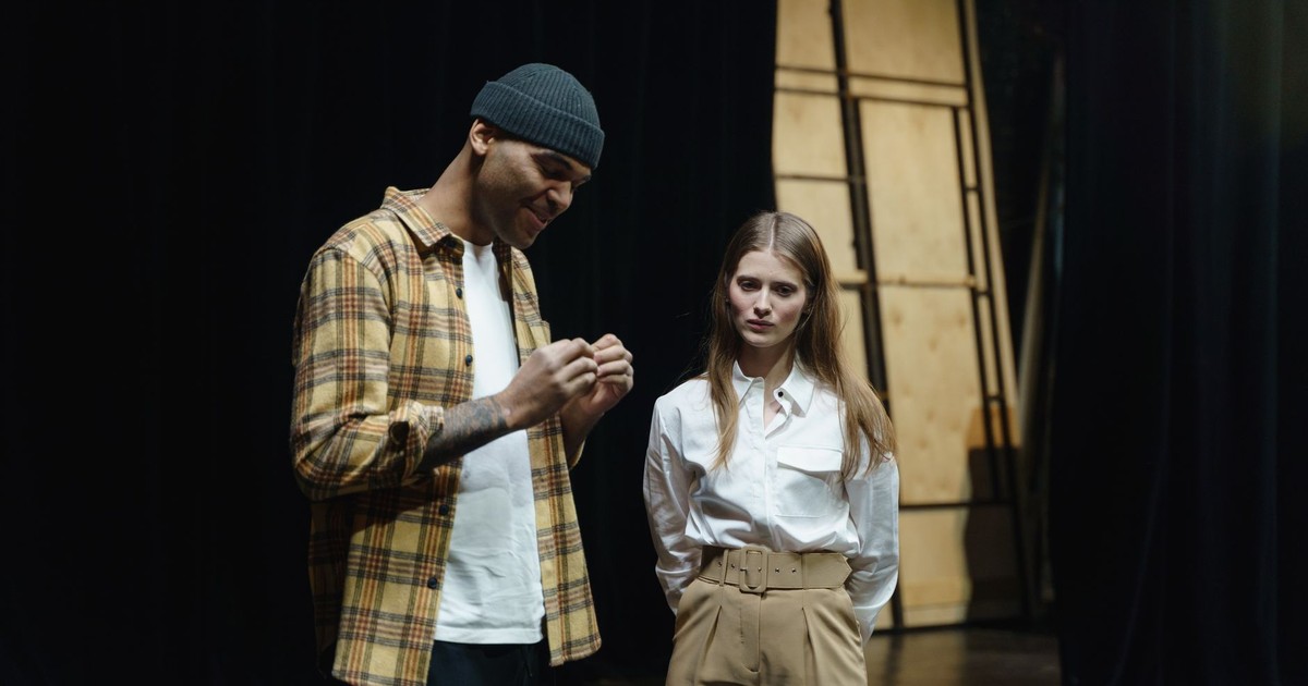 Two actors preparing for a scene during a theater rehearsal indoors.