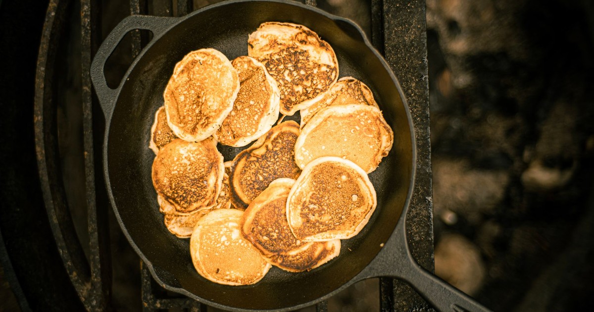 A delicious stack of golden pancakes cooked in a cast iron skillet, photographed from above.