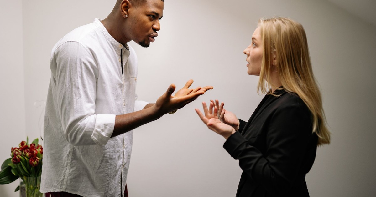 A man and woman engaged in a heated office argument, displaying emotion and intensity.