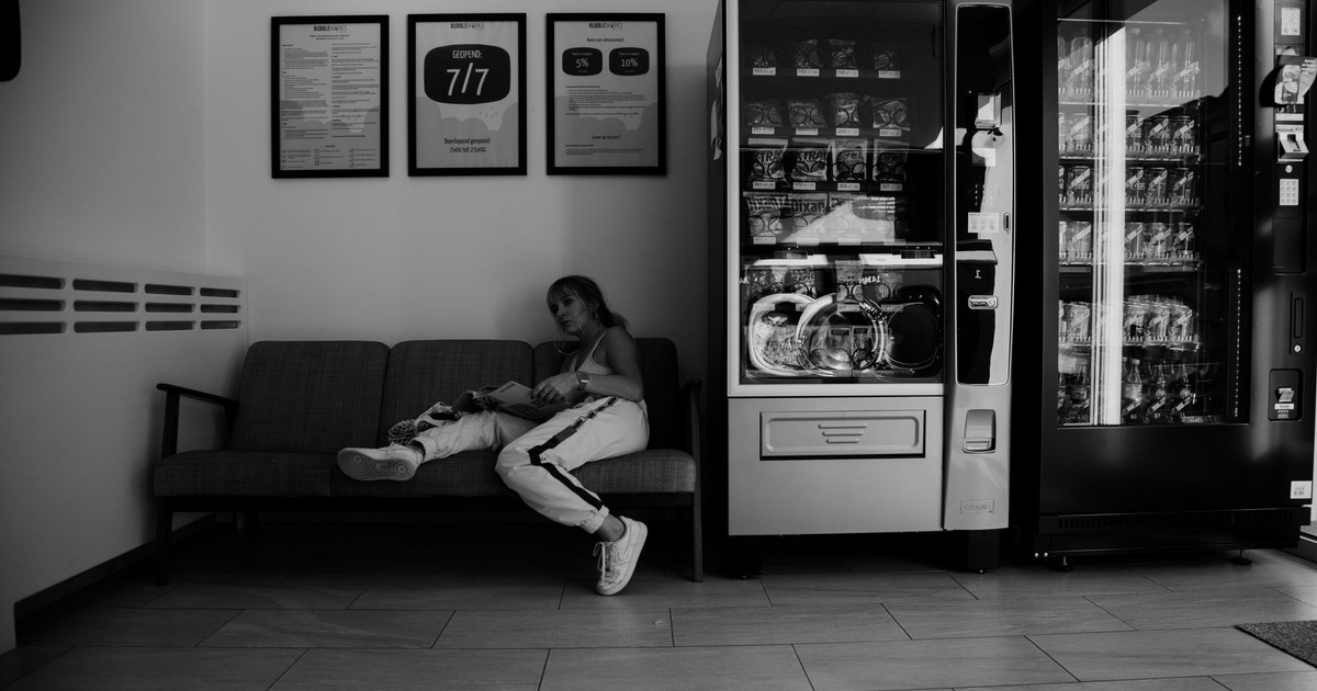 Black and white of young female reading newspaper while sitting on sofa in modern public shop