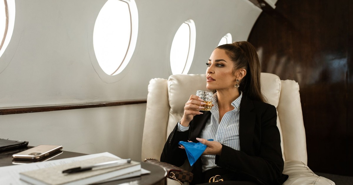 Sophisticated woman enjoying a drink on a luxury private jet, symbolizing success and elegance.