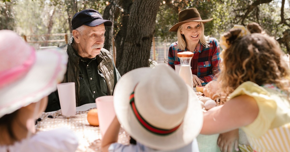 A joyful family picnic with adults and children enjoying a sunny day outdoors.