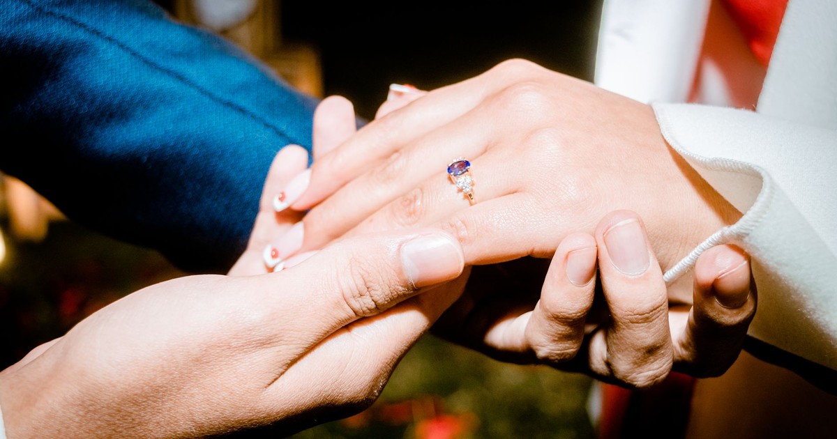 Close-up of hands during a romantic engagement proposal highlighting a beautiful ring.