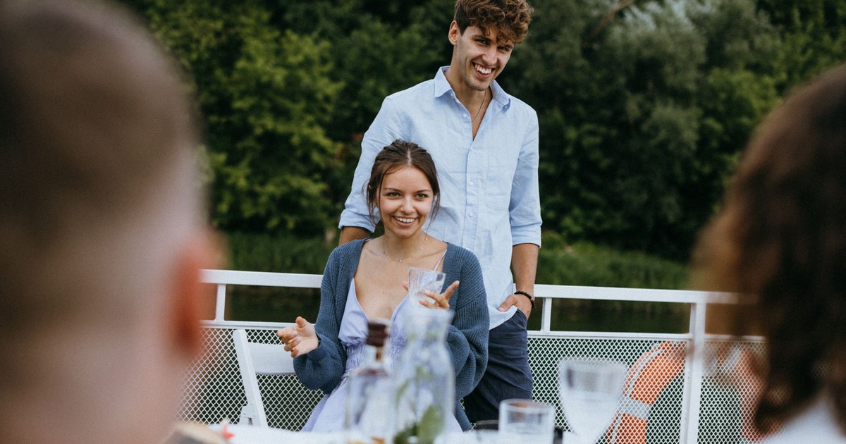 Cheerful young couple at an outdoor dinner with friends, enjoying lively conversation and good company.